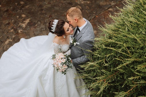Wedding Photo of the Bride in a White Dress and a Long Veil standing with the Groom.